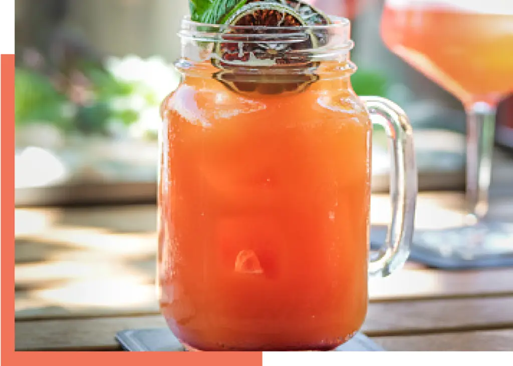 Orange passionfruit cocktail with dried fruit in a mason jar with handle